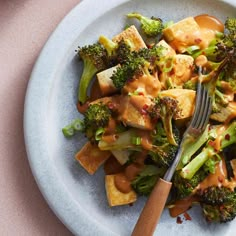 a white plate topped with broccoli and tofu covered in gravy