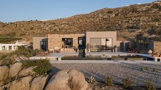 a house on the side of a mountain with a pool in front and rocks around it