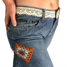 a woman wearing jeans with an embroidered patch on the back of her stomach and holding onto her belly