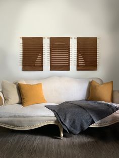 a white couch sitting in front of two brown and yellow pillows on top of it