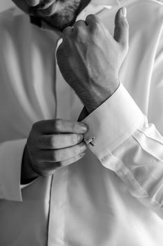 black and white photograph of a man adjusting his collar on his dress shirt, taken from the waist up