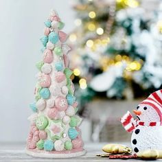 two small christmas trees on a table next to a snowman and a candy cane