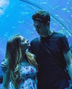 a man and woman standing in front of an aquarium