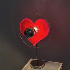 a red heart shaped object on top of a metal stand with a black ball in it