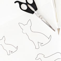 scissors and paper cut outs on top of a piece of paper with drawings of dogs