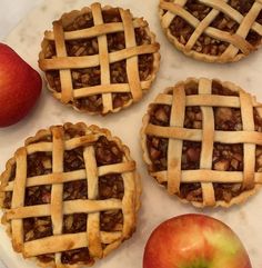 four apple pies sitting on top of a white counter next to an apple slice