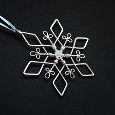 a snowflake ornament is shown on a black surface with silver wire