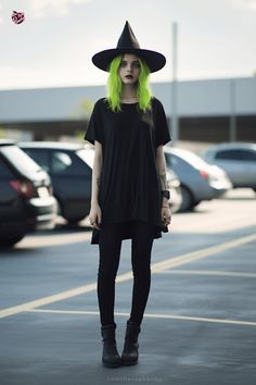 a woman with green hair wearing a witches hat and black dress standing in a parking lot