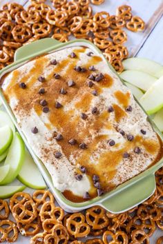 an apple dessert with chocolate chips and caramel on top, surrounded by pretzels