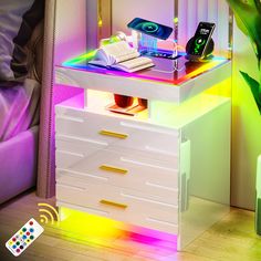 a white dresser with colorful lights on it and a remote control next to the drawers