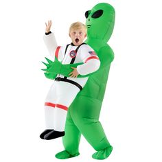 a boy in an inflatable costume standing next to a green alien