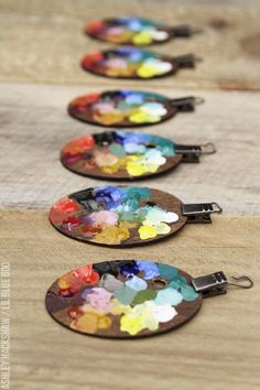 four wooden tags with different colors of paint on them sitting on top of a table