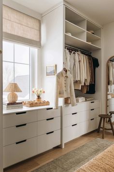 an organized closet with white drawers and clothes