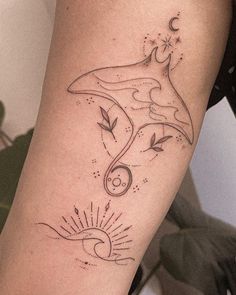 a woman's arm with a dolphin and sun tattoo design on the left side