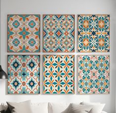 four colorful tiles are hanging on the wall above a couch in a room with white walls