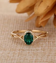 a ring with a green stone in the middle on a table next to some flowers