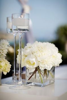 white flowers in vases and candles on a table