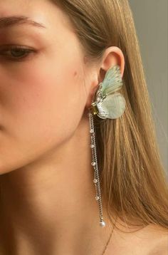 a close up of a person wearing earrings with a butterfly on the back of it