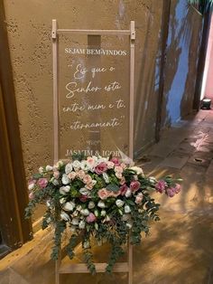 a sign that has flowers on it in front of a building with a planter