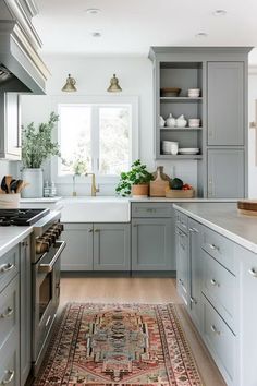 a kitchen with gray cabinets and an area rug on the floor in front of the stove