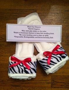 zebra print baby shoes with red ribbon and name tag on wooden floored room area