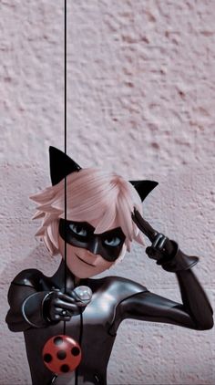 a catwoman doll hanging from a string with a ladybug on it's chest