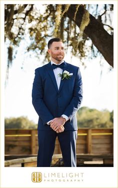 a man in a blue suit standing under a tree