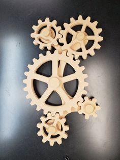 three wooden gears sitting on top of a black table next to a pair of scissors