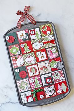 a christmas calendar on a cookie sheet with a red and green bow hanging from it