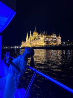 a person standing on a boat looking at the water in front of a large building