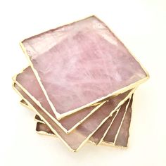 a stack of pink stone coasters sitting on top of a white table next to each other