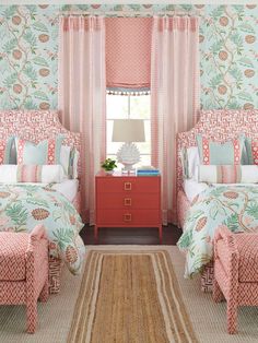 two beds in a room with pink and green wallpaper