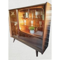 an old fashioned wooden china cabinet with glass doors and shelves filled with vases on top