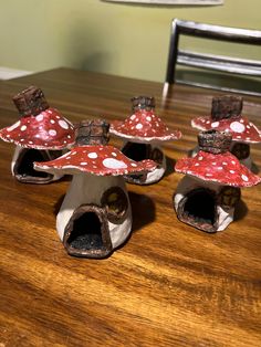 four little red mushrooms sitting on top of a wooden table