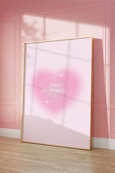 a pink wall with a white frame on it that says trust the process in front of it