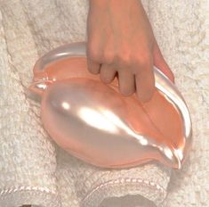 a woman's hand holding onto a shiny pink purse