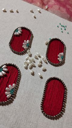 four pieces of embroidered fabric with flowers and pearls on them, sitting on a table