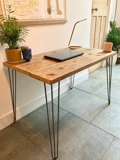 a wooden table with hairpin legs and a laptop on it in front of a wall