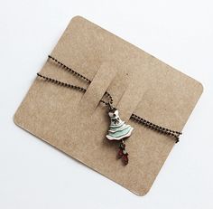 a piece of brown paper with a necklace on it and two charms attached to it