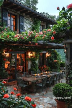 an outdoor dining area with potted plants and flowers on the roof, surrounded by greenery