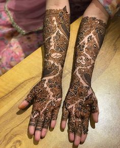 two hands with henna tattoos on them, one is showing the intricate pattern and the other has an elaborate design