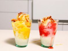 two glasses filled with food sitting on top of a white table next to each other