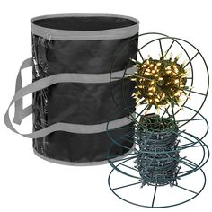 a christmas tree in a large black container with string lights on it and a wire basket