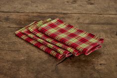 three red and green plaid napkins sitting on top of a wooden table