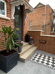 some plants are sitting on the steps in front of a house with black and white checkered flooring