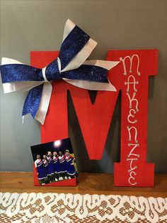 the letter m is decorated with cheerleaders and blue ribbon as well as a photo