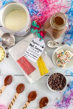 the ingredients to make hot chocolate are laid out on a table with confetti, marshmallows and sprinkles