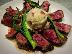 a white plate topped with meat and veggies next to a scoop of ice cream