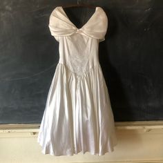 a white dress hanging up against a chalkboard