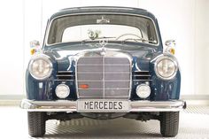 an old blue mercedes car is parked in a garage with the license plate on it's front